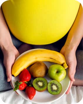 אישה בהריון מחזיקה צלחת עם פירות