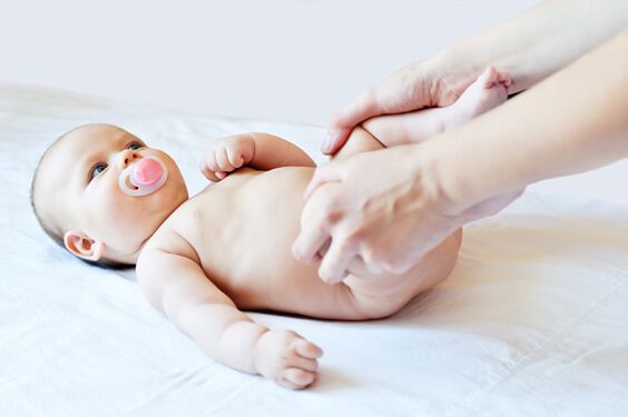 קרוב הברכיים של תינוקת עם מוצץ לבטן