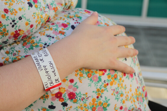 אישה בהריון עם צמיד של בית החולים על היד