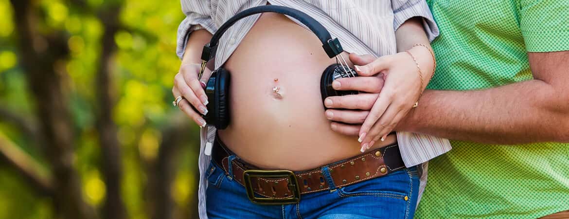 בעל ואישתו בהריון הניחו אוזניות על הבטן ההריונית