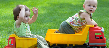 שני תינוקות משחקים יחד בדשא