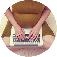 אשה בהריון יושבת על השטחי ומקלידה במחשב